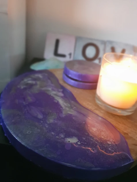 Purple marbled decorative tray and round coasters beside a lit candle