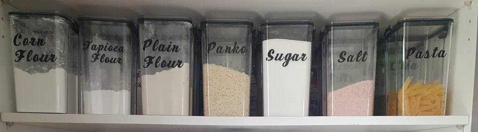 Clear pantry containers labelled Corn Flour, Tapioca Flour, Plain Flour, Panko, Sugar, Salt and Pasta