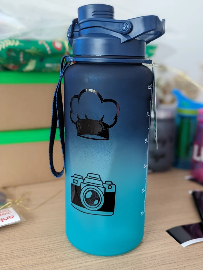 Blue-to-turquoise water bottle decorated with black chef's hat and camera designs